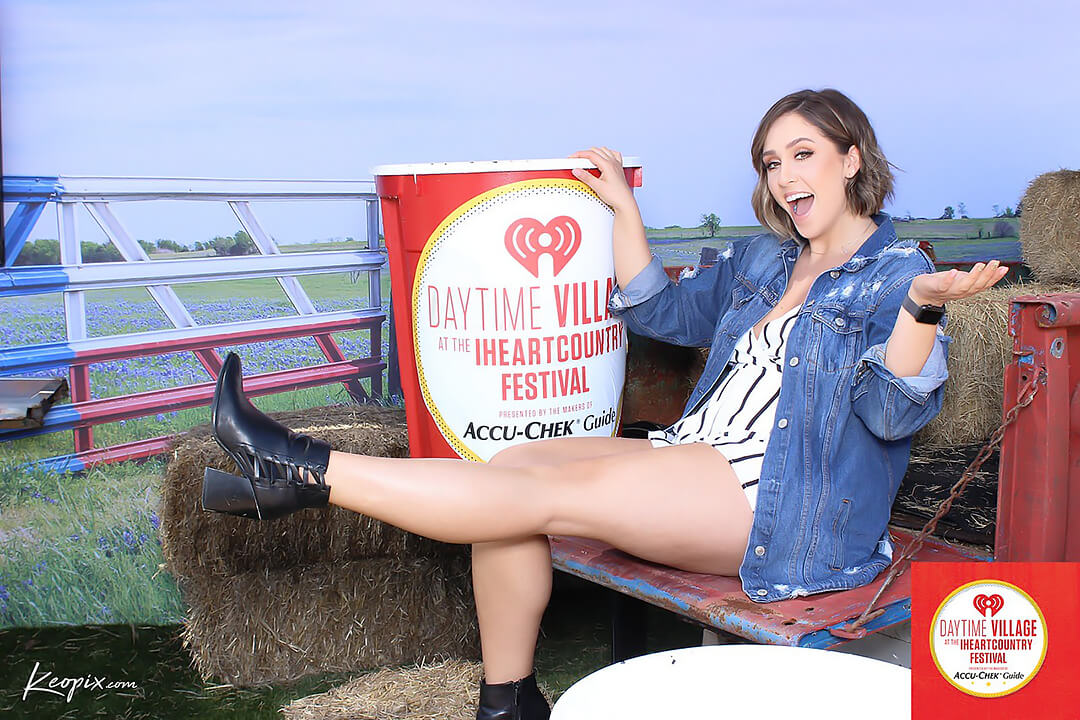 A woman poses on the tailgate of a pick-up truck at the iHeartCountry Festival