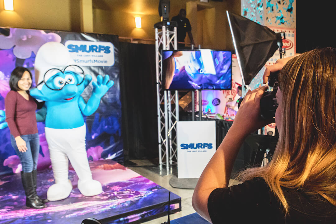 A Photographer captures a photo of a woman posing with one of the Smurfs
