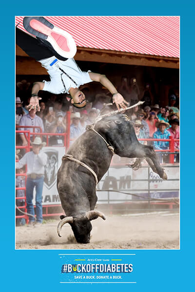 A green screen photo booth image where a man is upside down and is bucked off a bull at a rodeo