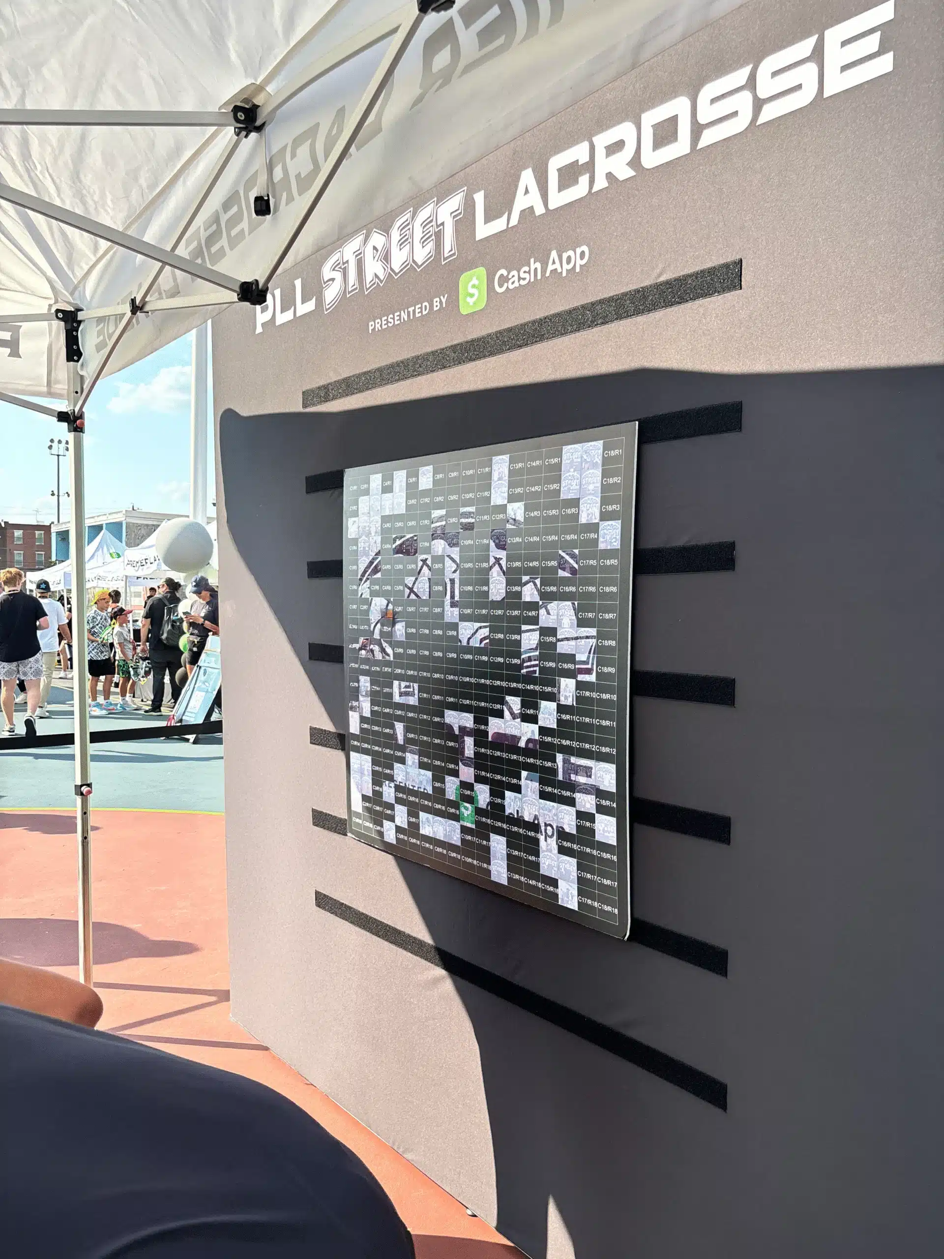 Keopix team setting up a mosaic photo wall display at an event, with black mounting grid and branded frame structure